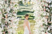 a jaw-dropping wedding arch covered with greenery, white and pink blooms and a view of the lake are fantastic for a garden wedding