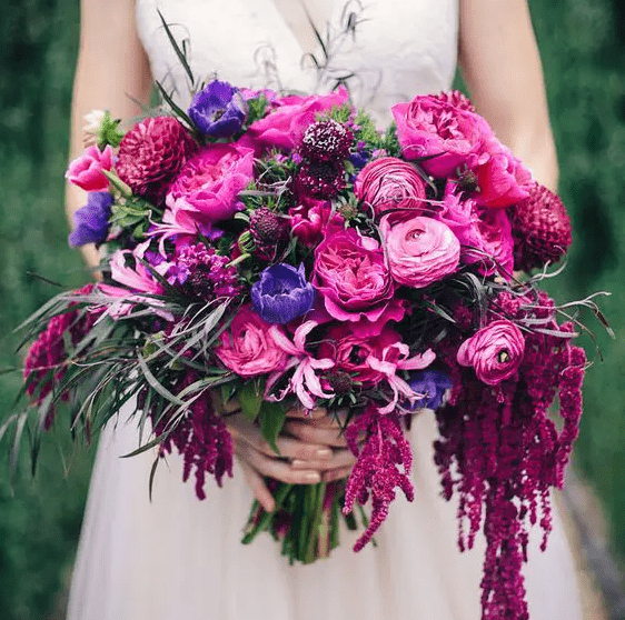 A jaw dropping wedding bouquet of hot pink, fuchsia and purple blooms and greenery is an amazing idea for the fall
