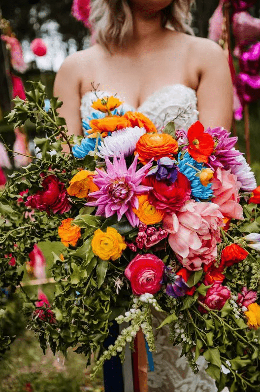 a jaw-dropping wedding bouquet of yellow and pink ranunculus, pink and blush blooms, burgundy ones and lots of greenery