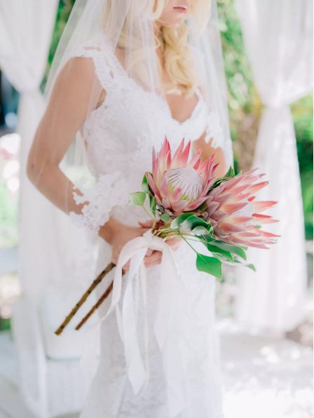 a long stem wedding bouquet of king proteas and white ribbons is a lovely idea for a tropical or summer bride