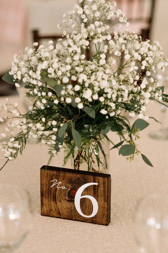 a lovely and simple baby's breath wedding centerpiece with some fern and eucalyptus is a cool idea for a rustic tablescape