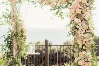 a lovely rustic wedding arch of branches, with greenery, twigs, blush and white rustic blooms is idea for spring or summer