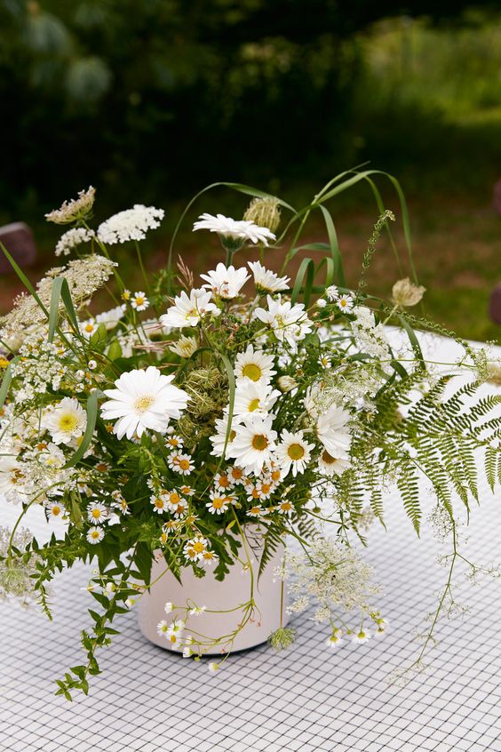 a lovely vintage-inspired wedding centerpiece of daisies, ferns and some wildflowers and seed pods is a very cool and romantic idea