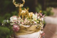 a naked wedding cake with gold touches, fresh blooms, greenery, twigs, berries and gold deer toppers is a perfect idea for an enchanted forest wedding