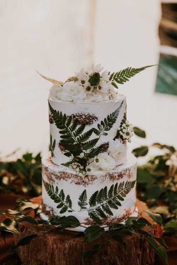 a naked wedding cake with pressed ferns and white blooms on top and decorating the tiers is a lovely idea for a forest wedding