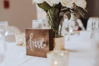 a pretty and simple wedding centerpiece of a gilded vase and white roses plus a wooden table number is a chic and easy solution