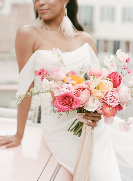 a pretty summer wedding bouquet of pink and blush roses, pink and orange ranunculus and some sweet peas