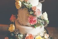 a quirky enchanted forest wedding cake with fresh white, yellow and pink blooms, greenery and seed pods is bold and cool