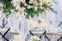 a refined garden wedding centerpiece of much greenery, white roses and orchids is a lush and very beautiful solution