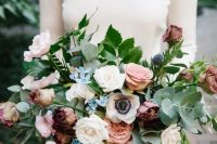 a romantic autumn wedding bouquet of blush, white and mauve roses, blue blooms, white anemones, thistles and greenery