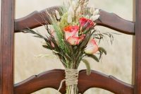 a rustic wedding mini bouquet with red roses, dried grasses and greenery with a twine wrap is a very cool and simple arrangement to make yourself