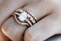 a stunning wedding ring stack with an oval shaped diamond, two lower rings with smaller diamonds and no diamonds and an arched upper ring with some rhinestones