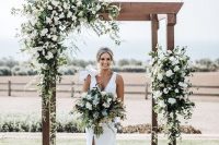 a stylish rustic wedding arch of wooden slabs, greenery and white blooms is a timeless idea for a rustic wedding