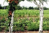 a summer rustic wedding arch of birch branches, greenery and sunflowers is a fun and bold idea to rock and you can DIY it
