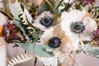a textural wedding centerpiece of white anemones and dark burgundy blooms, foliage and pale leaves is a stylish idea for summer