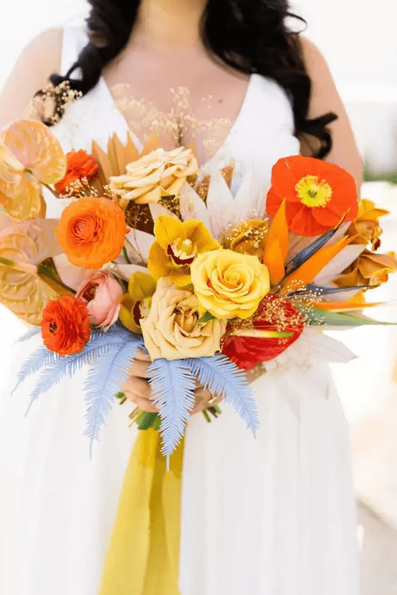 a vibrant wedding bouquet of orange, yellow and red blooms including ranunculus, roses and anthurium plis colorful leaves