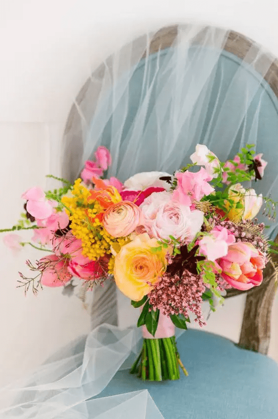a vibrant wedding bouquet with pink, yellow, blush blooms, deep purple ones and yellow ones plus some greenery