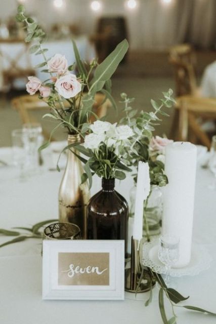 a whimsy cluster wedding centerpiece of blush and white garden roses and greenery, various candles and gilded candleholders
