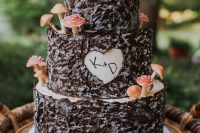 an enchanted forest wedding cake covered with bark, with a cutout heart and mini mushrooms is a lovely and natural-looking idea