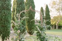 an enchanting secret garden wedding arch of a whimsy shape, with greenery and lots of blush blooms climbing up the arch