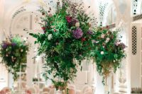 beautiful and bright tall wedding centerpieces of much greenery and bright flowers create a magical and charming ambience in the space