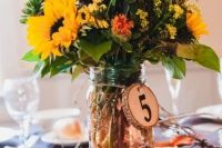 05 a bright and cute rustic fall wedding centerpiece of a jar with pebbles, orange, rust, yellow and deep purple blooms and leaves