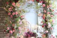 06 a bright overgrown flower wedding arch with lots of greenery, pink, burgundy and deep red blooms will wow you and your guests