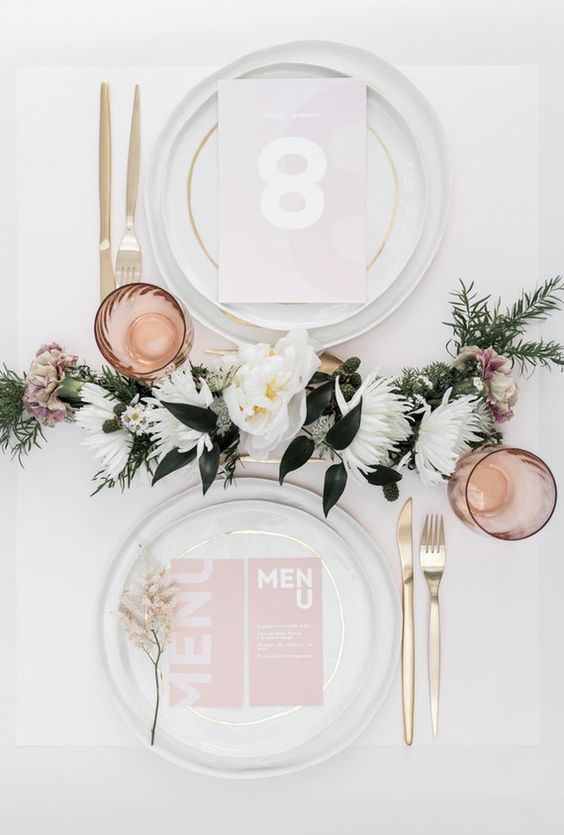 a delicate and elegant modern bridal shower tablescape with neutral porcelain, pink stationery, gold cutlery, a floral table runner and pink glasses