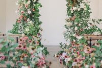 08 a gorgeous wedding ceremony space with lots of pink and blush overgrown wedding blooms and a matching lush wedding arch with greenery