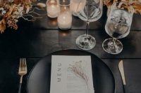 10 a chic modern fall wedding tablescape with an uncovered table, dried blooms and twigs, black plates and cutlery, candles
