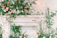 10 a fireplace space with lots of overgrown pink and peach blooms and greenery is a gorgeous wedding ceremony space