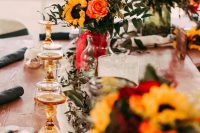 19 a bright fall wedding tablescape with amber glasses, sunflowers, red and pink roses and lots of eucalyptus is very chic and cozy