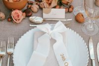 19 a modern fall wedding tablescape with neutral linens, nuts, pink and peachy roses, pink candles and elegant cutlery