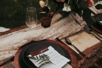 23 a moody rustic fall wedding tablescape with a wooden charger, a burlap napkin, blooms and greenery and black plates