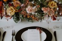 23 a stylish modern fall wedding tablescape with a black charger, black cutlery, lovely blush, peachy, rust and yellow blooms and greenery
