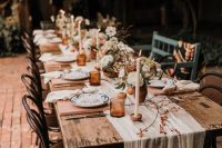 24 a relaxed rustic fall wedding tablescape with a neutral runner, amber glasses, terracotta vases with neutral and pastel blooms, candles and menus