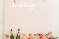 28 a glam modern bridal shower bubbly bar with a pink sign, greenery, pink floral arrangements and some drinks and glasses
