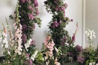 30 a garden-like wedding ceremony space is done with greenery, blush, pink and white overgrown blooms, an arch covered with greenery and lilac