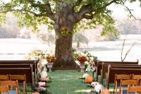 33 a simple and cozy rustic fall wedding ceremony space with pumpkins and fall leaves lining up the aisle and more leaves on the living tree