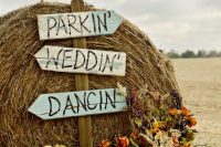 cool rustic fall decor with hay, signs, pumpkins, fall blooms and greenery is a very cute and cozy idea for a summer or fall wedding