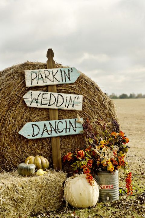 cool rustic fall decor with hay, signs, pumpkins, fall blooms and greenery is a very cute and cozy idea for a summer or fall wedding