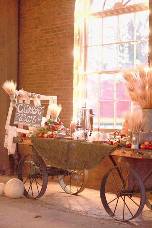 a chic fall wedding cider bar created of a cart, wheat, apples and pallets and drinks is ideal for a rustic wedding