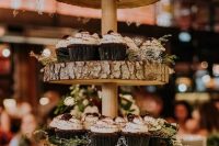 49 a wood slice stand with greenery and delicious cupcakes plus a naked wedding cake with chocolate drip on top