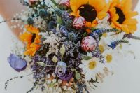 a beautiful and colorful wedding bouquet of pink and purple blooms,chamomiles, thistles, sunflowers and baby’s breath is amazing
