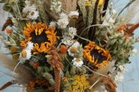 a beautiful dried flower wedding bouquet with pampas grass, sunflowers, astilbe, daisies, greenery for a fall or summer boho bride
