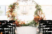a beautiful round fall rustic wedding arch with greenery and bold foliage, with pampas grass is a very cool and stylish idea
