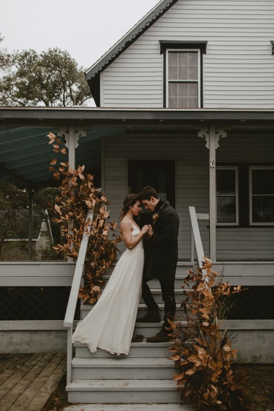 a boho fall wedding altar created right on the porch, with dried leaves, blooms and grasses is a very cool yet moody idea