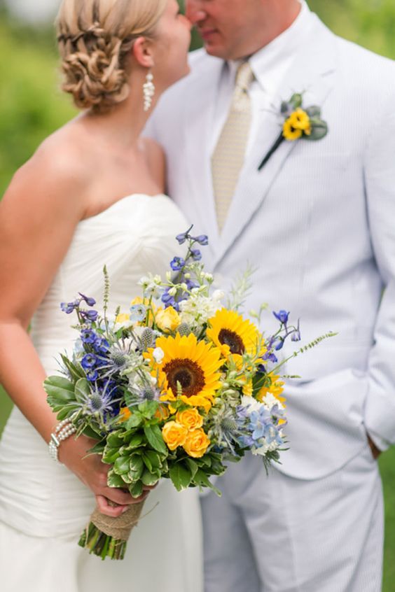 a bright wedding bouquet with sunflowers, purple blooms, thistles and greenery is a cool idea for a summer wedding with a rustic feel