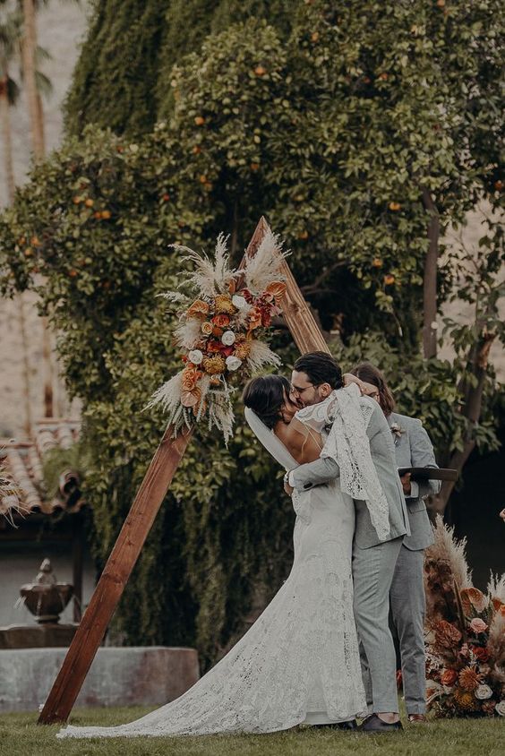 a chic fall boho wedding arch with yellow, pink, blush blooms, pampas grass and dried leaves is amazing