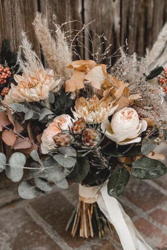 a chic neutral wedding bouquet with blush peonies, dried eucalytus and leaves, pampas grass, twigs and white ribbons for a summer or fall bride